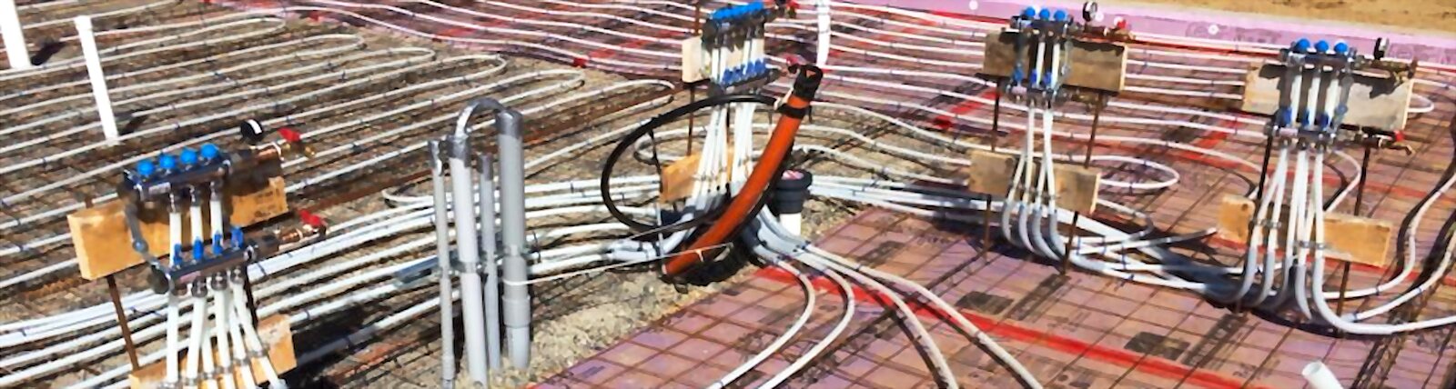 Radiant floor heating manifolds and PEX tubing laid over insulation before a slab pour